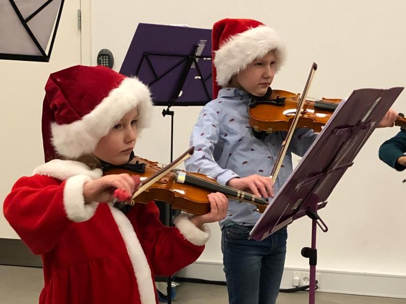 To børn spiller violin med nissehuer på.